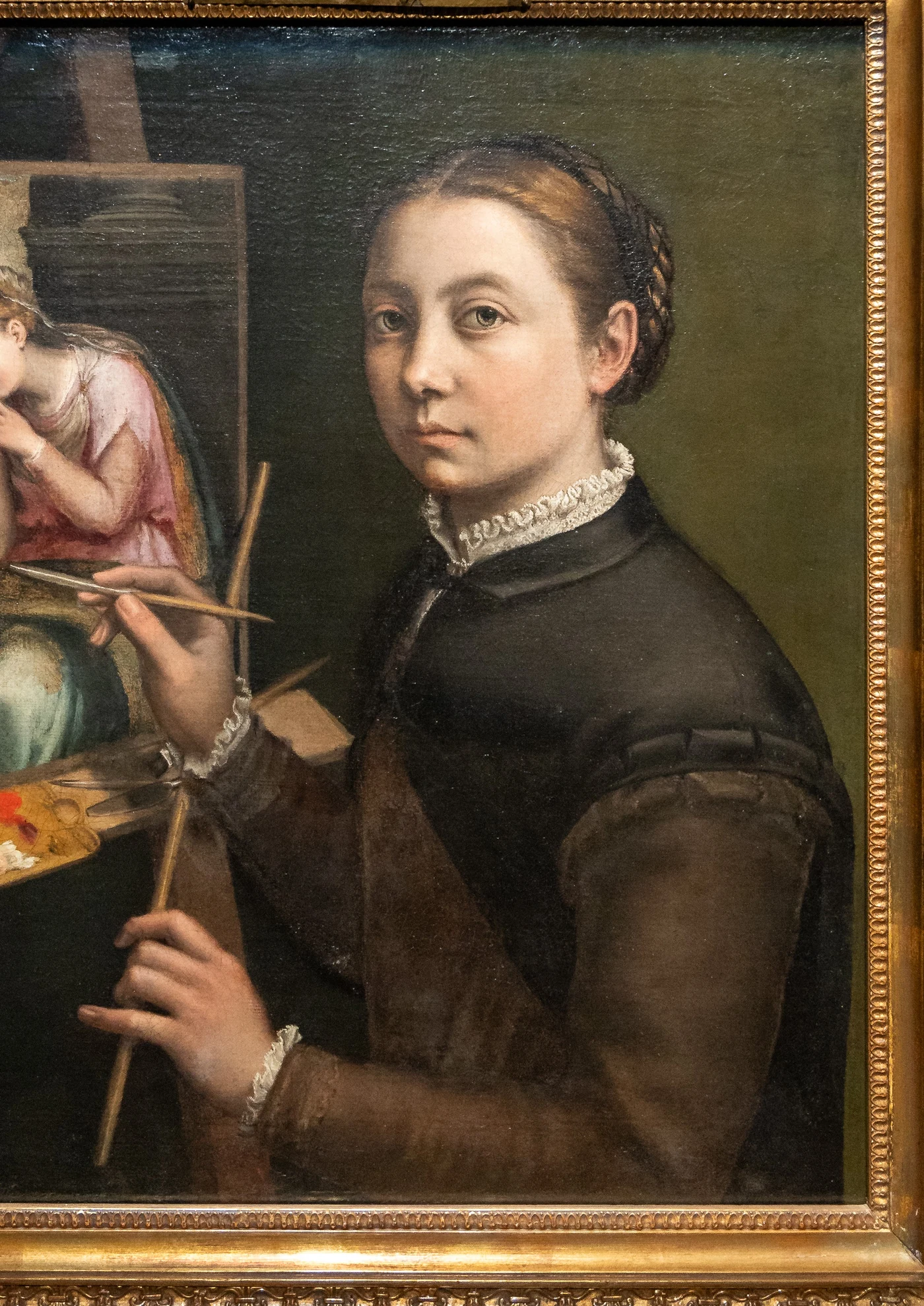Sofonisba Anguissola se représente en buste, un pinceau à la main, peignant un tableau sur son chevalet.