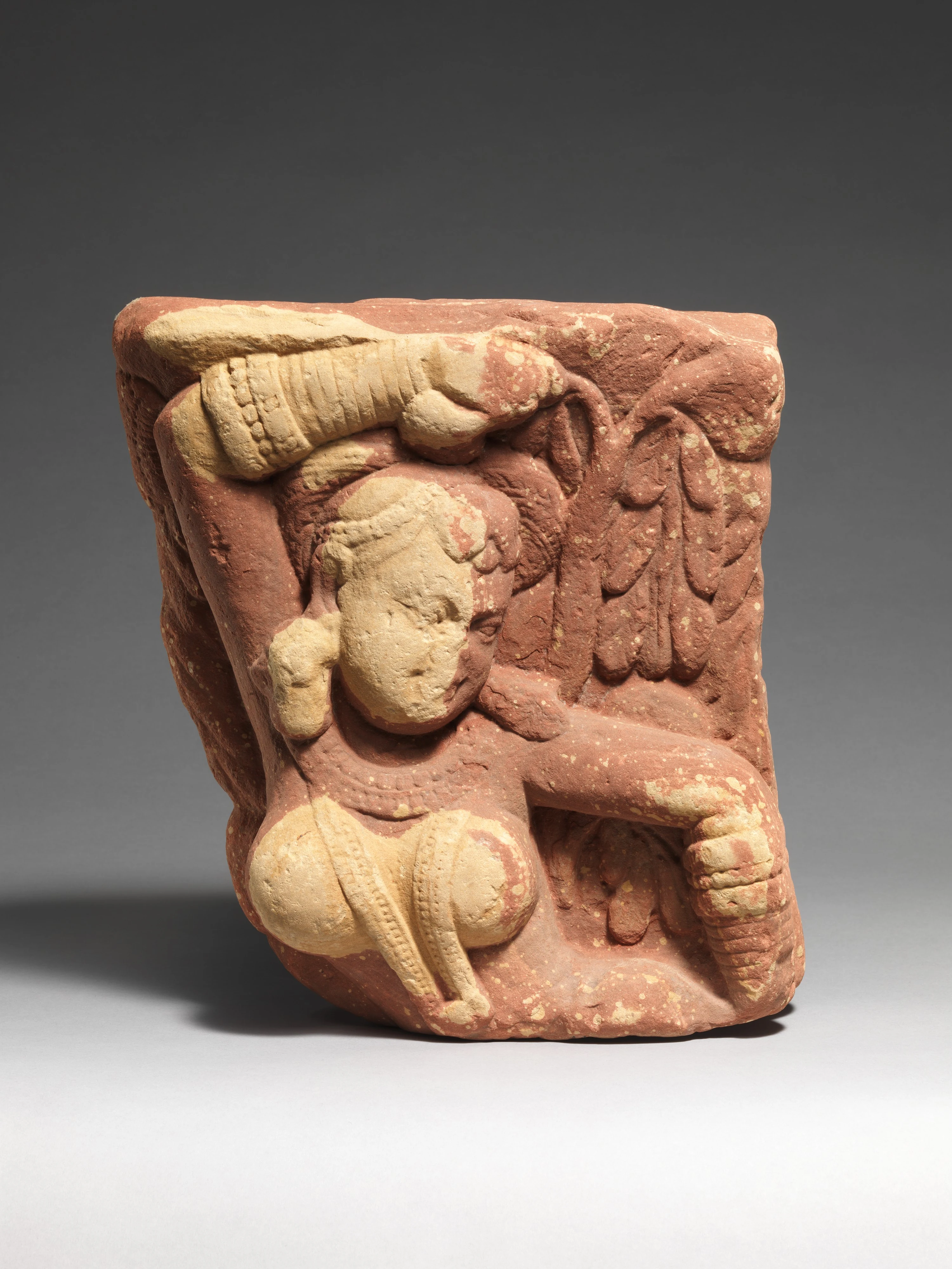 Fragment de grès rouge sculpté représentant une yakshi, figure féminine au bras levé posé sur une branche d'arbre en fleur.